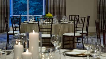 A dining table set for six with chairs, candles, and a window view.