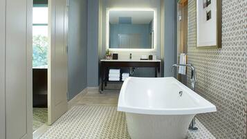 A modern bathroom with a freestanding bathtub, a large mirror, and a vanity with two sinks.