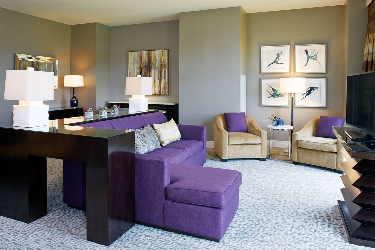 Una sala de estar moderna con un sofá modular, dos sillones, una mesa de centro y un televisor de pantalla plana.
