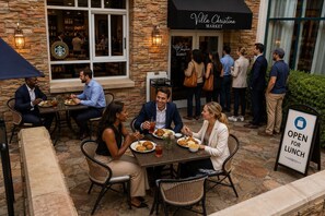 An outdoor dining area with stone walls, wicker chairs, and tables. - Hyatt Regency Atlanta Perimeter at Villa Christina (Atlanta)