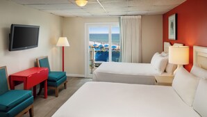 A hotel room with two beds, a TV, a desk, and a view of the beach. - Pleasant View Inn (Westerly)