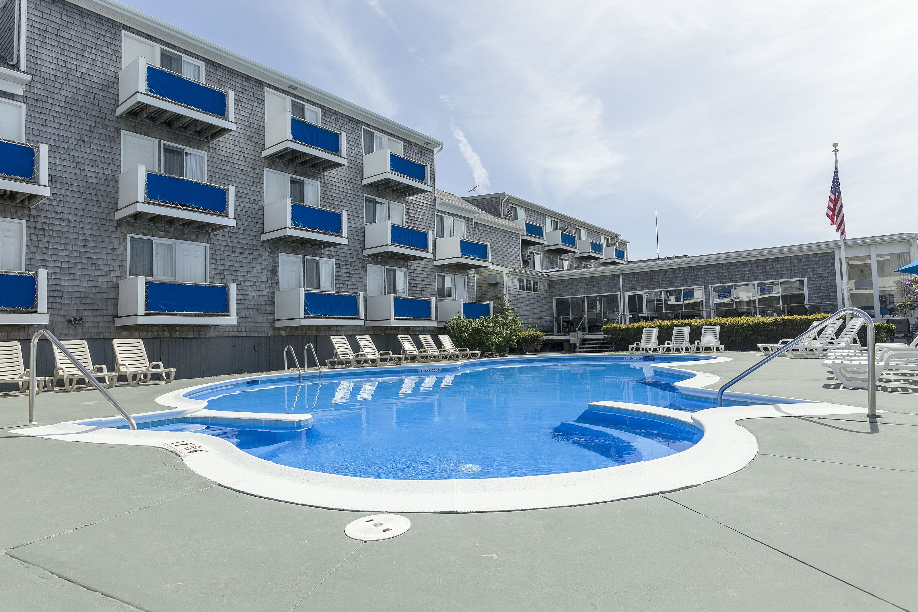 Una piscina con sdraio e un edificio con balconi.