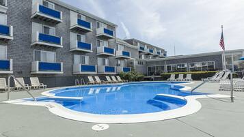 Una piscina con sdraio e un edificio con balconi.