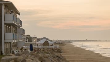 Un hotel frente a la playa con edificios de varios pisos, una playa de arena y un litoral rocoso.