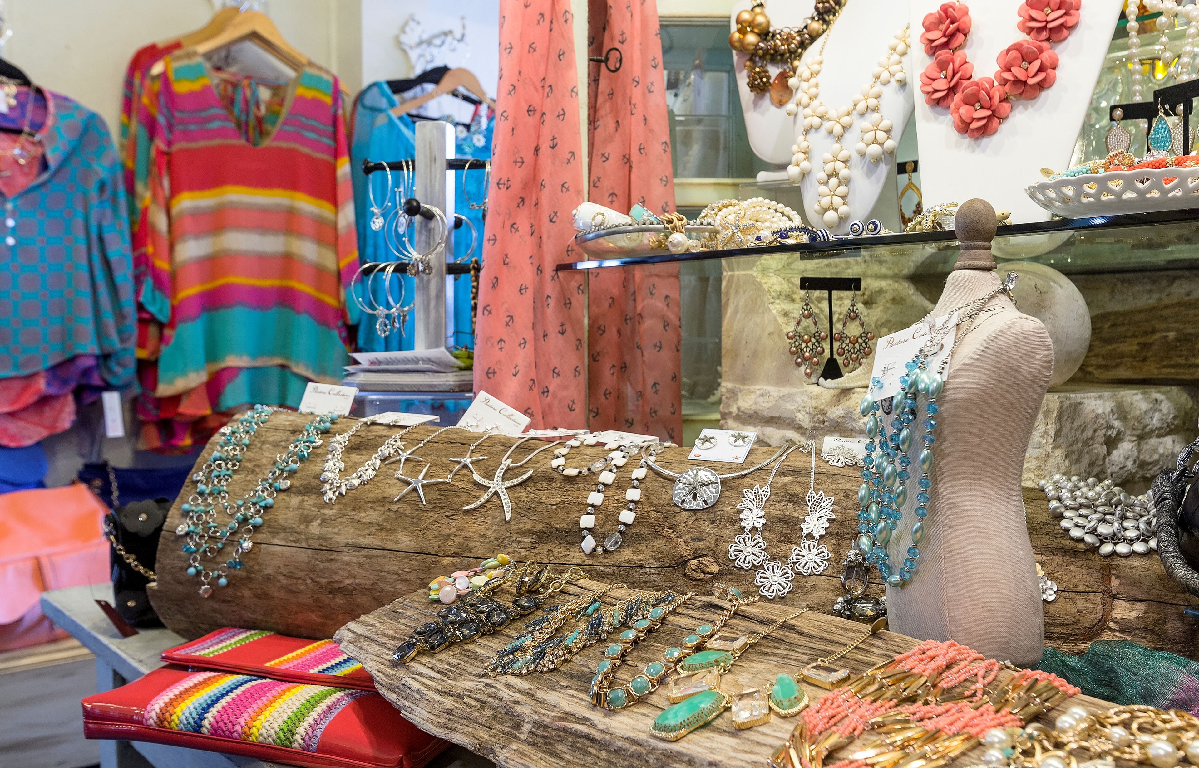 A jewelry display with various necklaces and bracelets on a wooden stand.