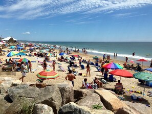 A crowded beach with numerous umbrellas and people.