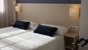 Une chambre d’hôtel avec deux lits, une tête de lit, des lampes de chevet et une table de chevet.