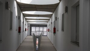 Un long couloir étroit, agrémenté de plusieurs hublots circulaires dans le plafond, d’extincteurs fixés aux murs et offrant une vue sur l’extérieur grâce à de grandes fenêtres au bout.