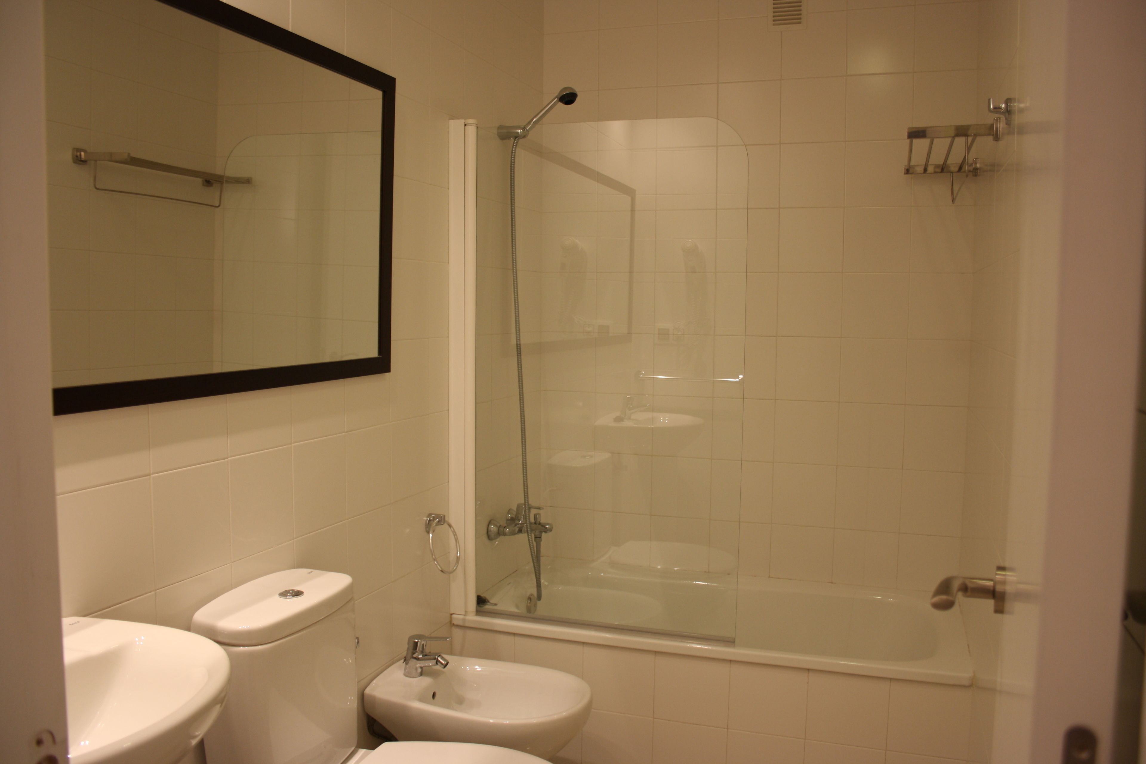 Et badeværelse med toilet, bidet og brusekabine i glas.