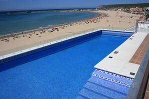 Una piscina con vista a una playa y al océano.