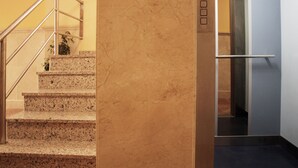 Una scalinata in marmo con ringhiere in metallo che conduce a un ascensore.