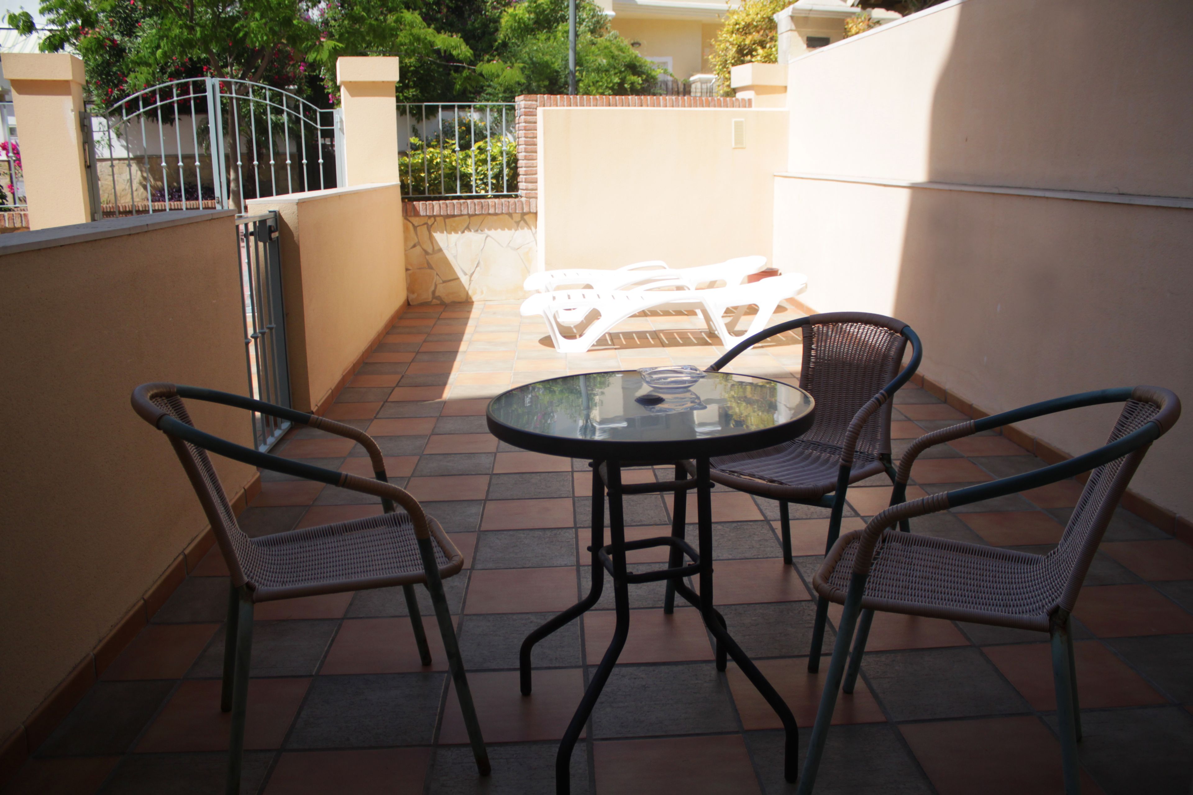 A patio with a round table and four wicker chairs.
