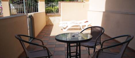 Un patio con una mesa redonda y cuatro sillas de mimbre.