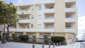 Un edificio residenziale a più piani con balconi, un muro in pietra e un albero sullo sfondo.