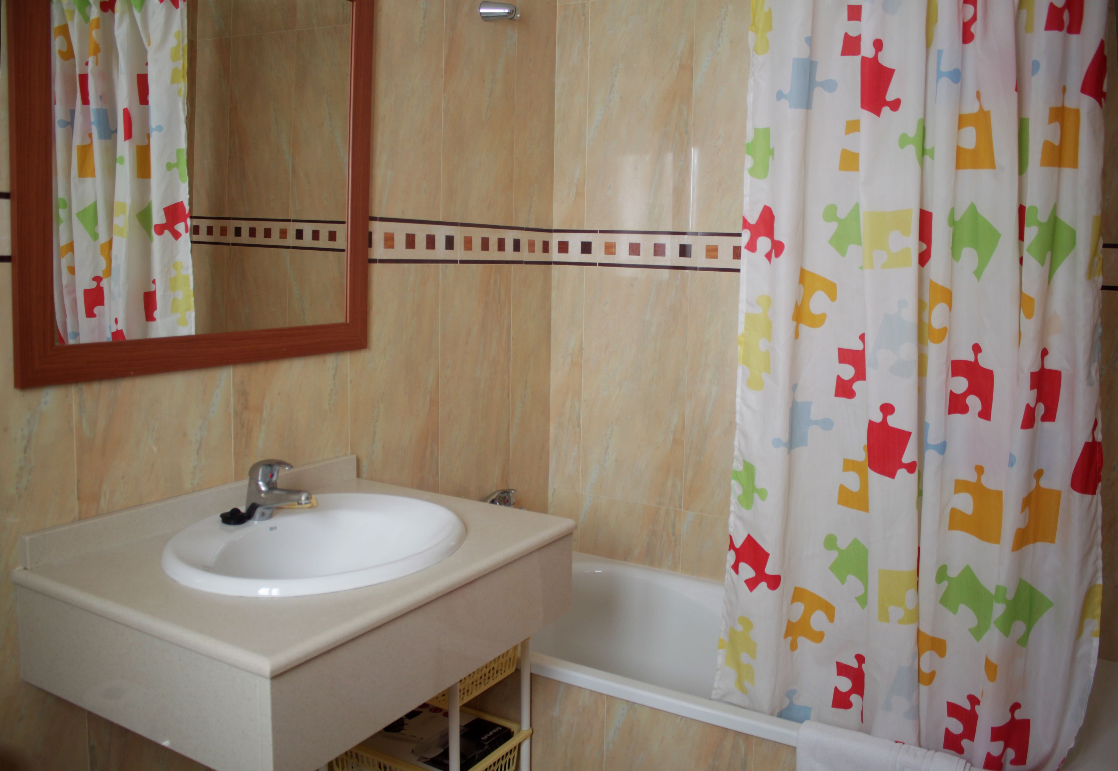 A bathroom with a sink, mirror, and bathtub.