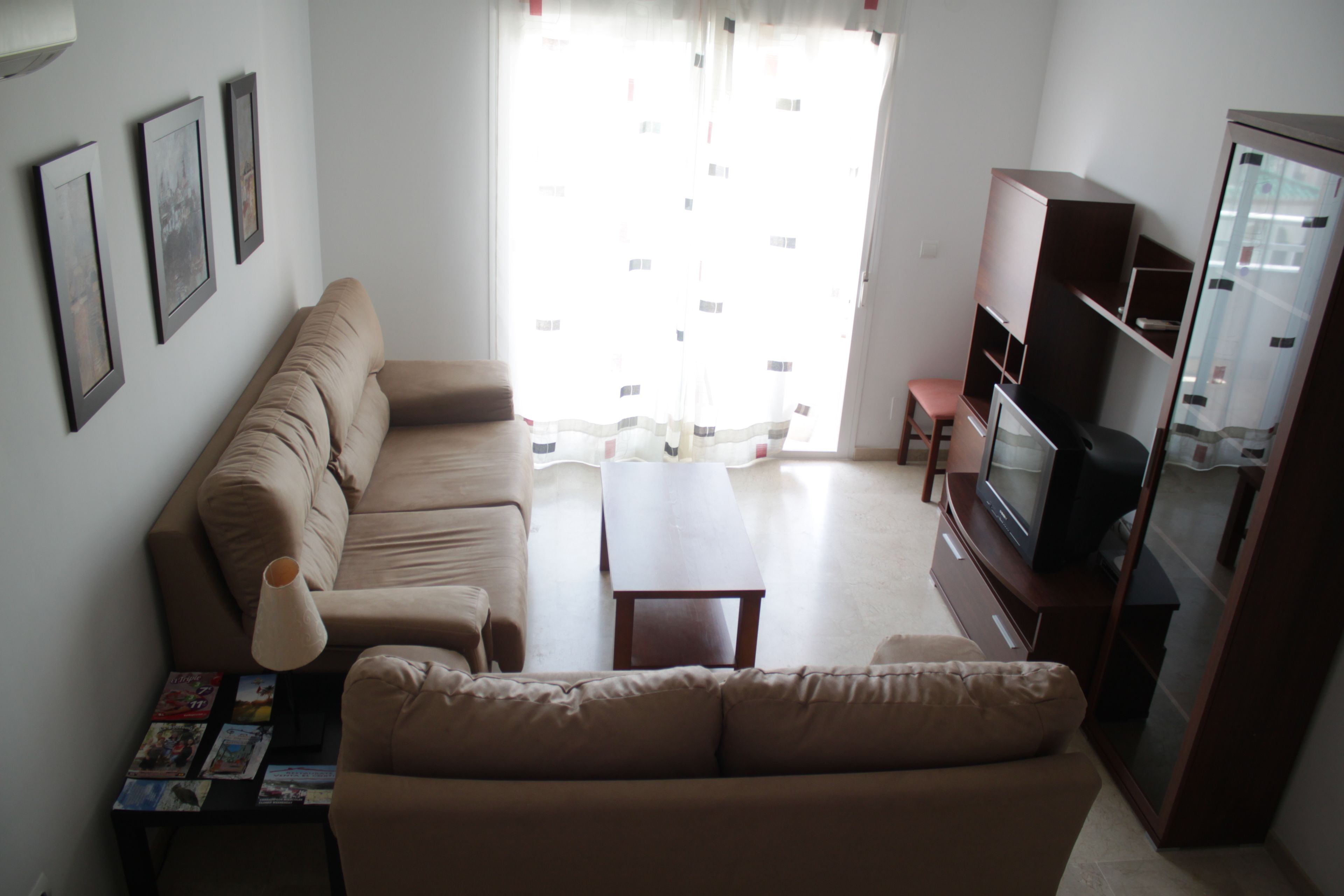 Una sala de estar con sofá, mesa de centro, televisor y aparador.