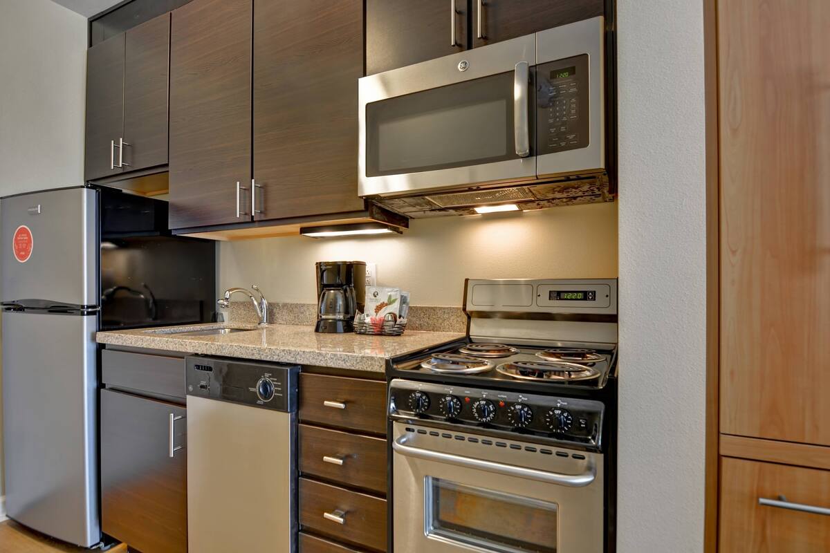 A modern kitchen with stainless steel appliances, including a refrigerator, dishwasher, microwave, and stove.
