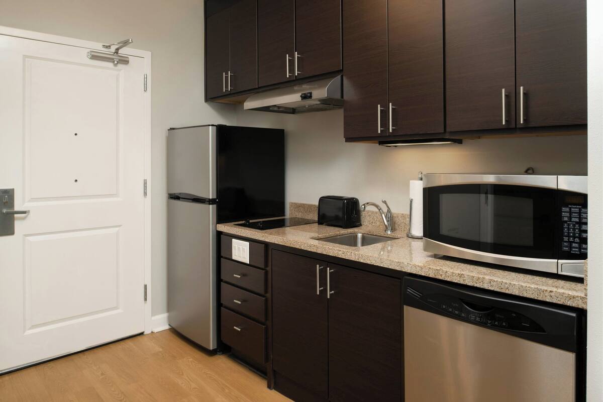 A modern kitchen with dark wooden cabinets, stainless steel appliances, and a granite countertop.