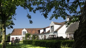 A traditional house with a sloped roof, surrounded by a well-maintained lawn and mature trees. - B&B Pronkenburg (Bruges)
