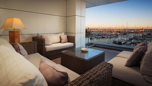 A balcony with wicker furniture, a table, and a lamp. - Las Suites de Puerto Sherry (El Puerto de Santa Maria)