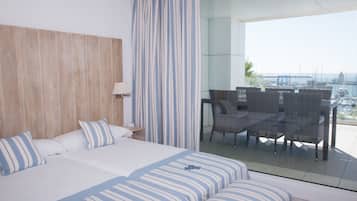 Ein Hotelzimmer mit einem großen Bett, einem Balkon mit Korbmöbeln und Blick auf den Yachthafen.
