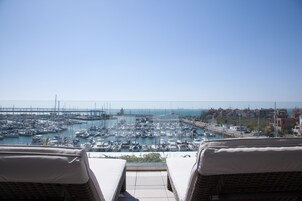 Un puerto deportivo con numerosos barcos amarrados, cielo despejado y vista al mar.