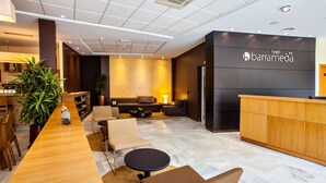 A hotel lobby with a reception desk, seating area, and a large potted plant. - Hotel Barrameda (Sanlucar de Barrameda)