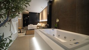 A modern bathroom with a large bathtub, a sofa, and a potted plant. - Hotel Barrameda (Sanlucar de Barrameda)