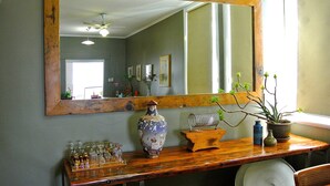 A room with a wooden dresser, a large mirror, a vase, and a potted plant. - Vine Valley Inn (Cessnock)