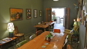 A dining area with a wooden table, chairs, and a lamp. There are framed pictures on the wall and a plant on the table. - Vine Valley Inn (Cessnock)