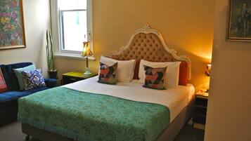 A neatly made bed with patterned pillows, a green bedspread, and a decorative headboard.