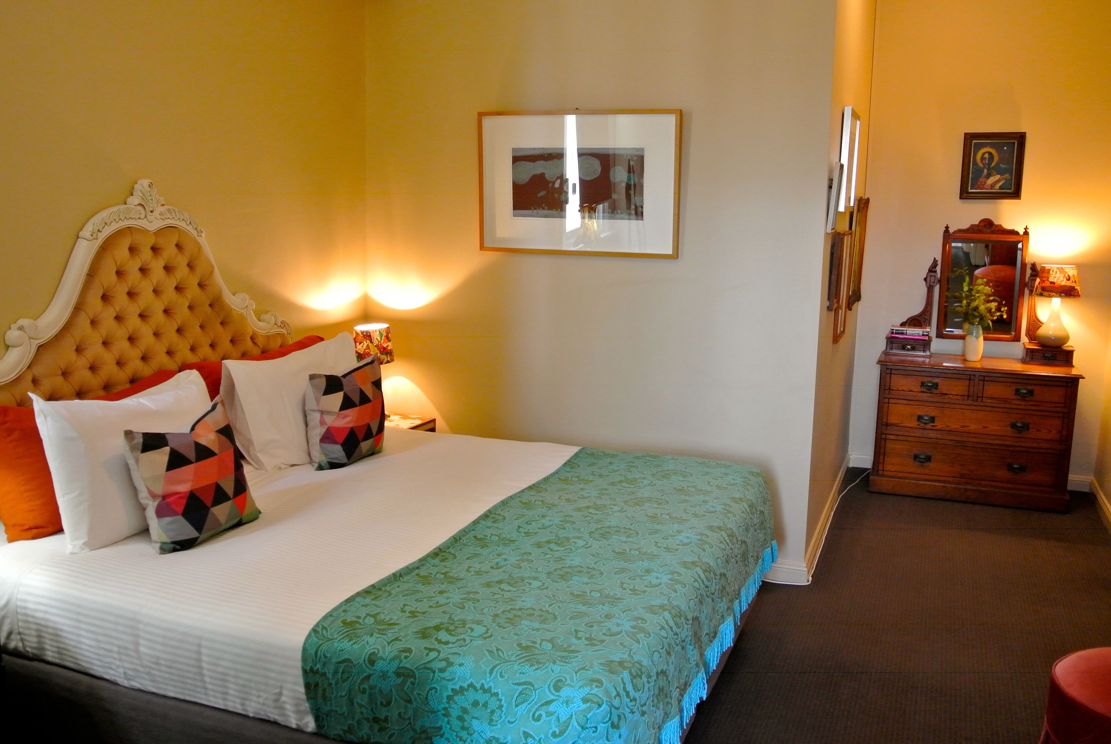Une chambre d’hôtel avec un grand lit, une commode en bois et un tableau encadré au mur.