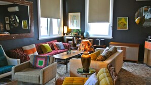 A cozy living room with a sofa, armchairs, a coffee table, and a lamp. - Vine Valley Inn (Cessnock)