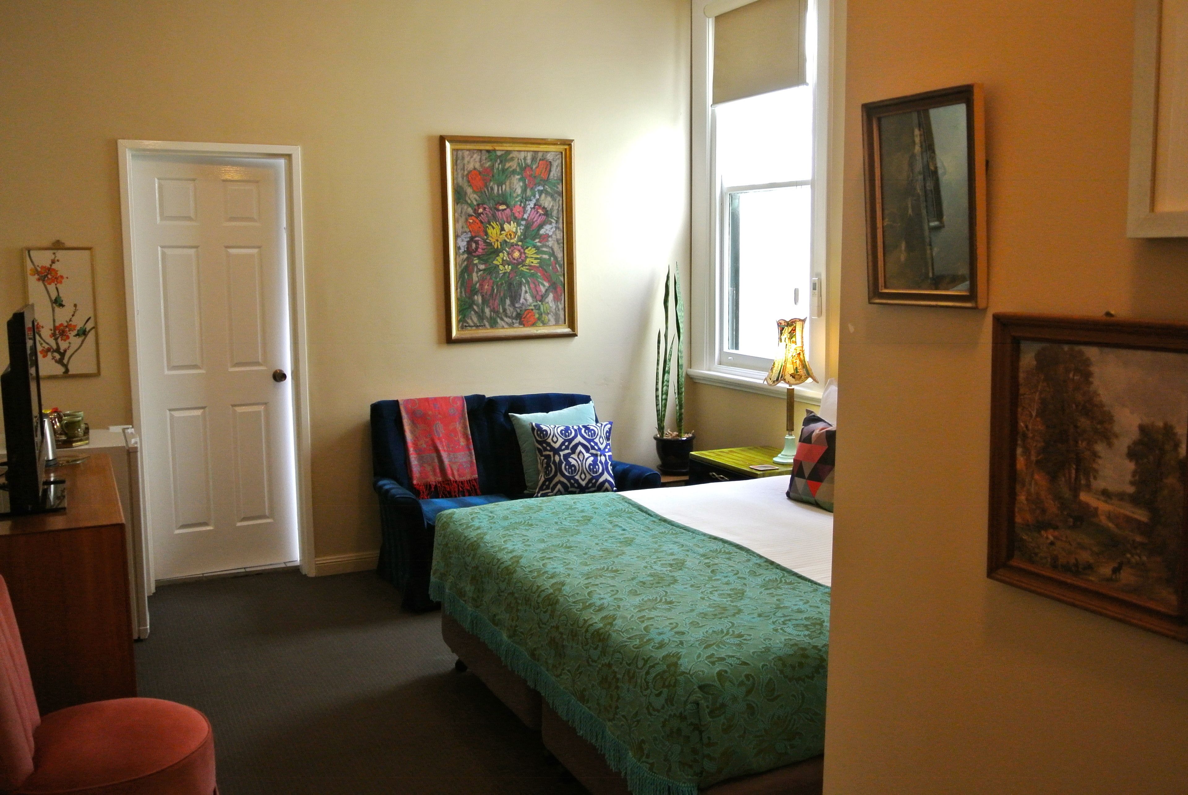A bedroom with a bed, a chair, a desk, a door, and a window.