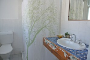 A bathroom with a white toilet, a sink with a blue tiled countertop, and a mirror above the sink.