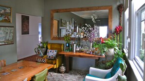 A dining area with a wooden table, chairs, and a mirror above. - Vine Valley Inn (Cessnock)