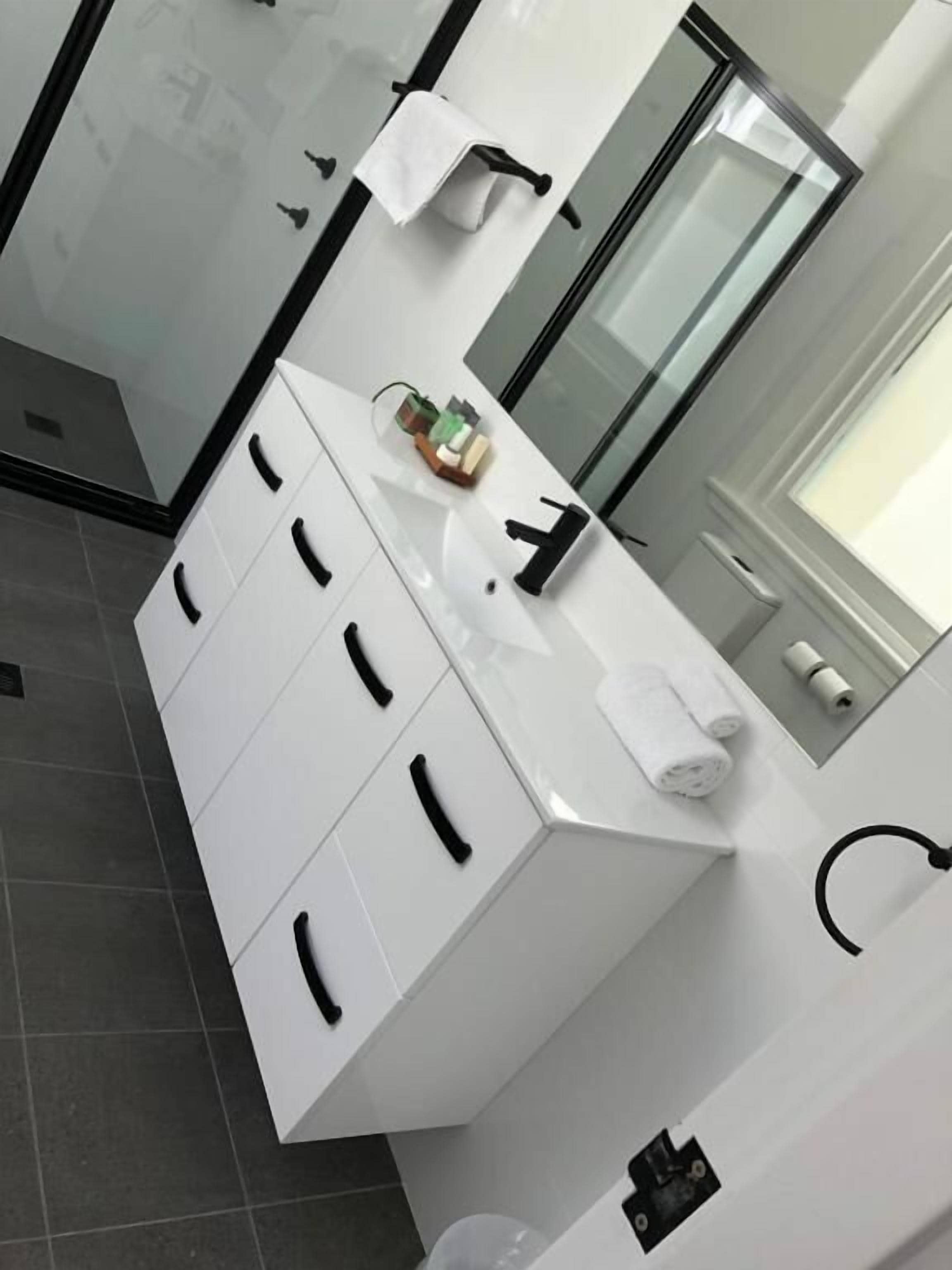 Un baño moderno con tocador blanco, espejo y perchero.