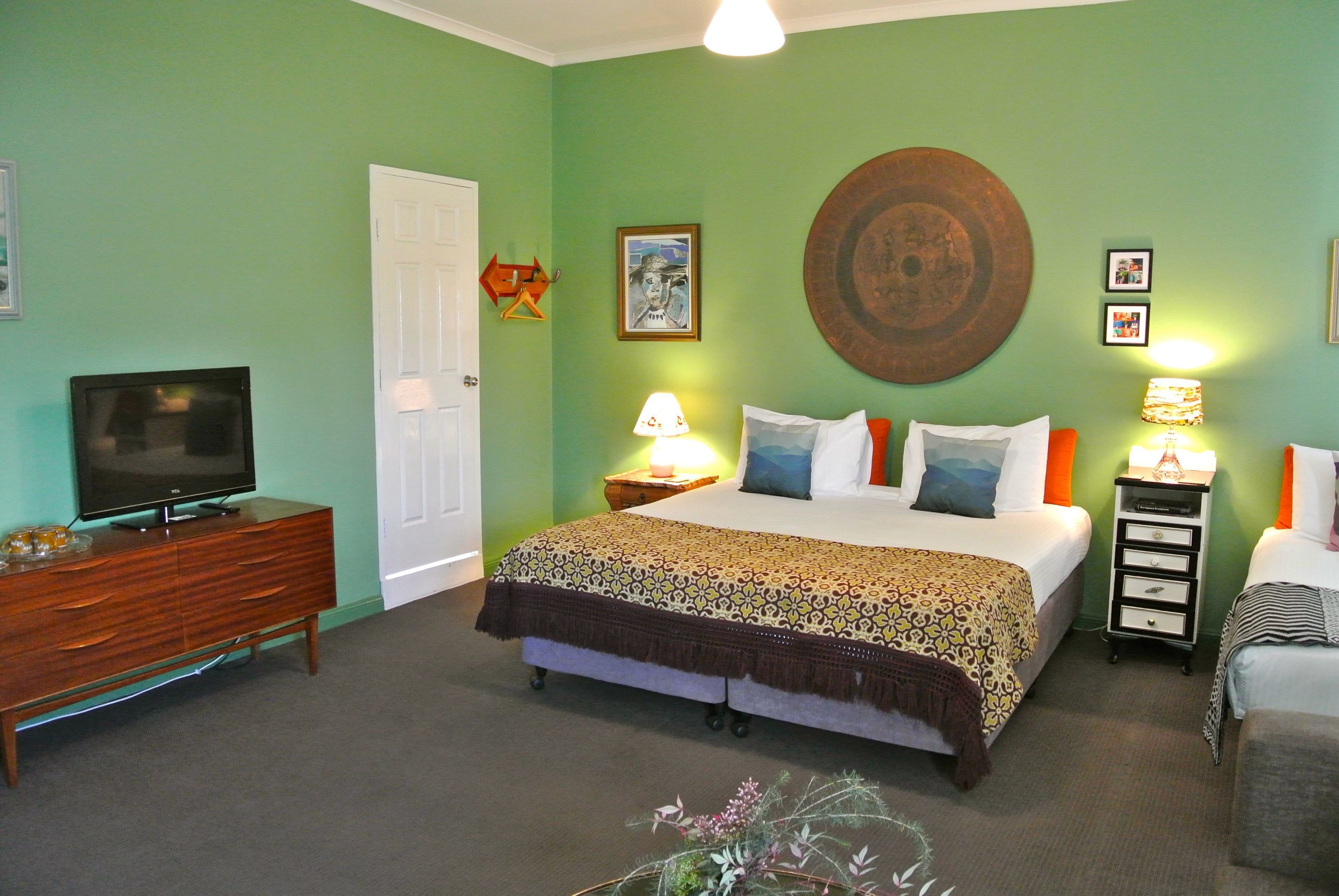 A bedroom with a bed, bedside tables, a television, and a door.
