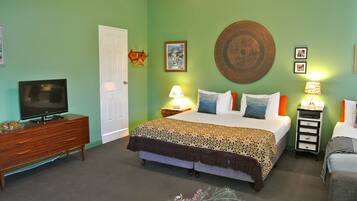 A bedroom with a bed, bedside tables, a television, and a door.