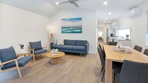 A modern living room with a sofa, chairs, a coffee table, and a dining table. - Reflections Massy Greene - Holiday Park (Brunswick Heads)