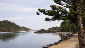 A calm lake with a sandy beach, a rocky outcrop, and a boat docked on the shore.