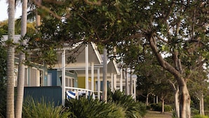 A house with a porch, surrounded by palm trees and green plants. - Reflections Brunswick Head - Holiday Park (Brunswick Heads)