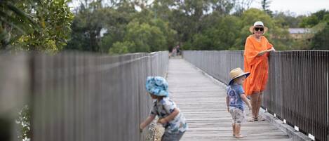 A wooden bridge with metal railings, surrounded by greenery.