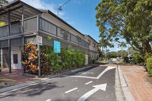 A street view with a building featuring a balcony, a shared zone sign, and a directional arrow on the road. - Reflections Brunswick Head - Holiday Park (Brunswick Heads)