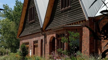 Une maison à deux étages, dotée d’un toit à forte pente, d’une façade en briques et d’un porche à colonnes à l’avant.