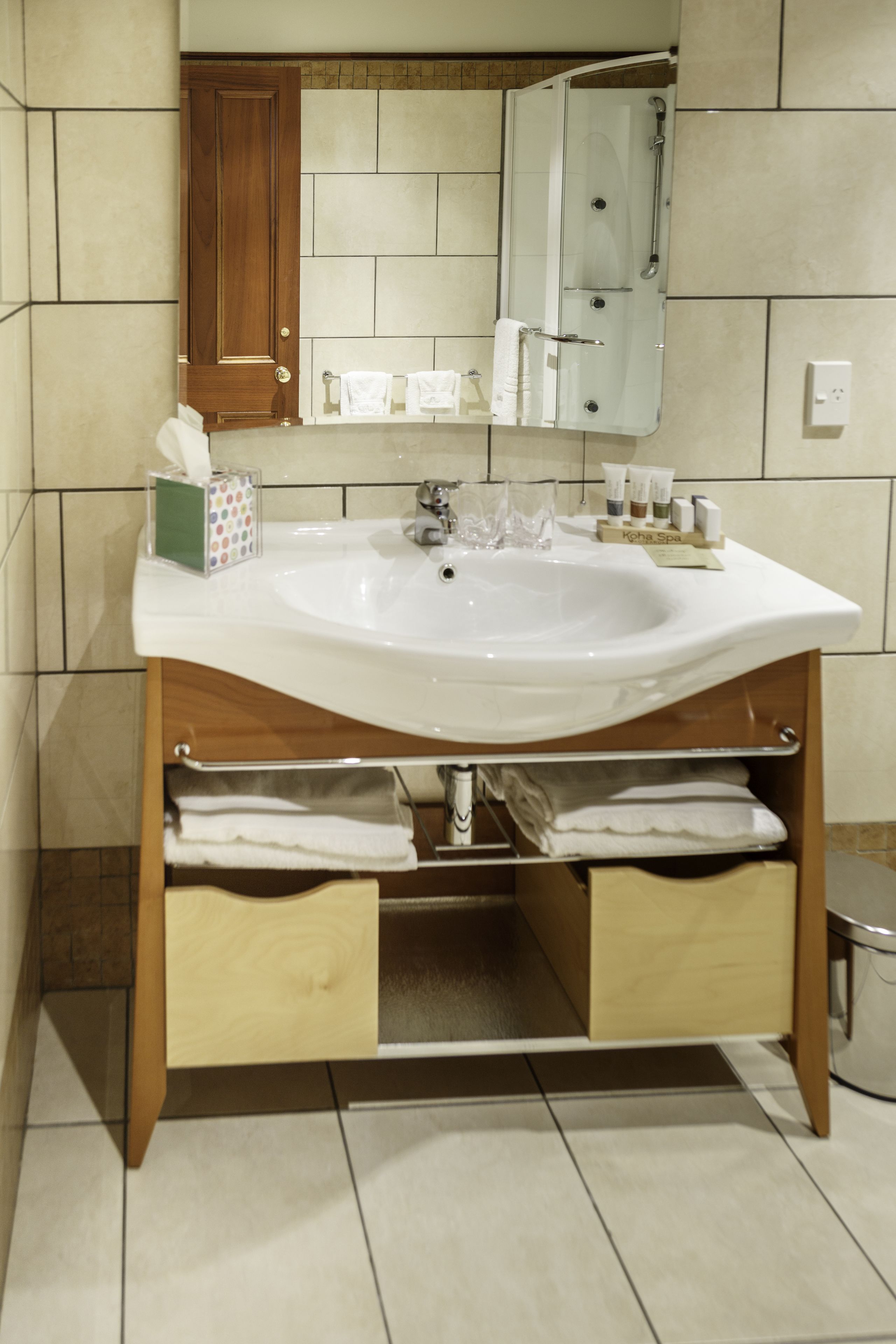 A bathroom with a white sink, wooden cabinet, and tiled walls.