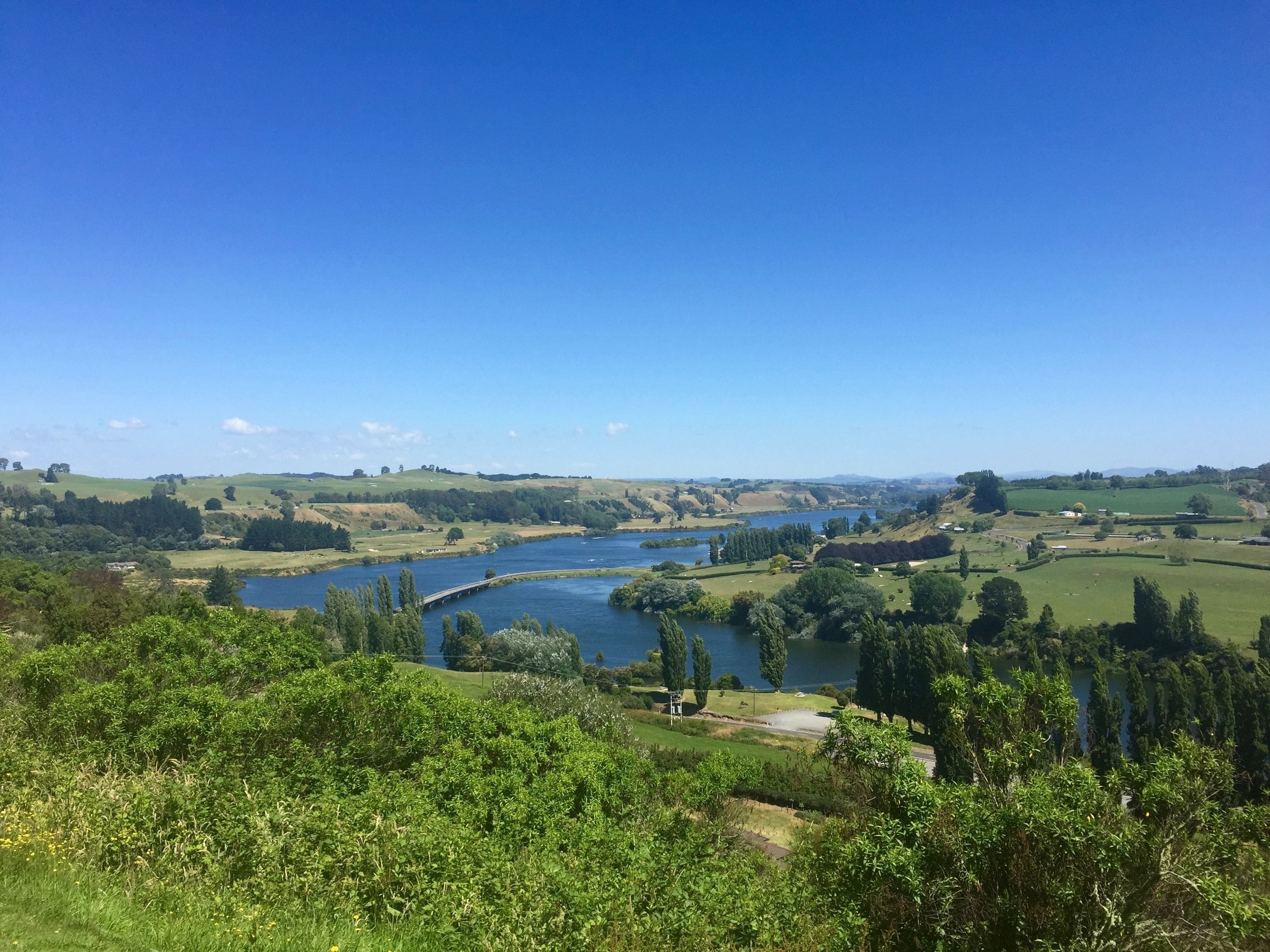 Un paisaje pintoresco con un río, campos verdes y árboles.
