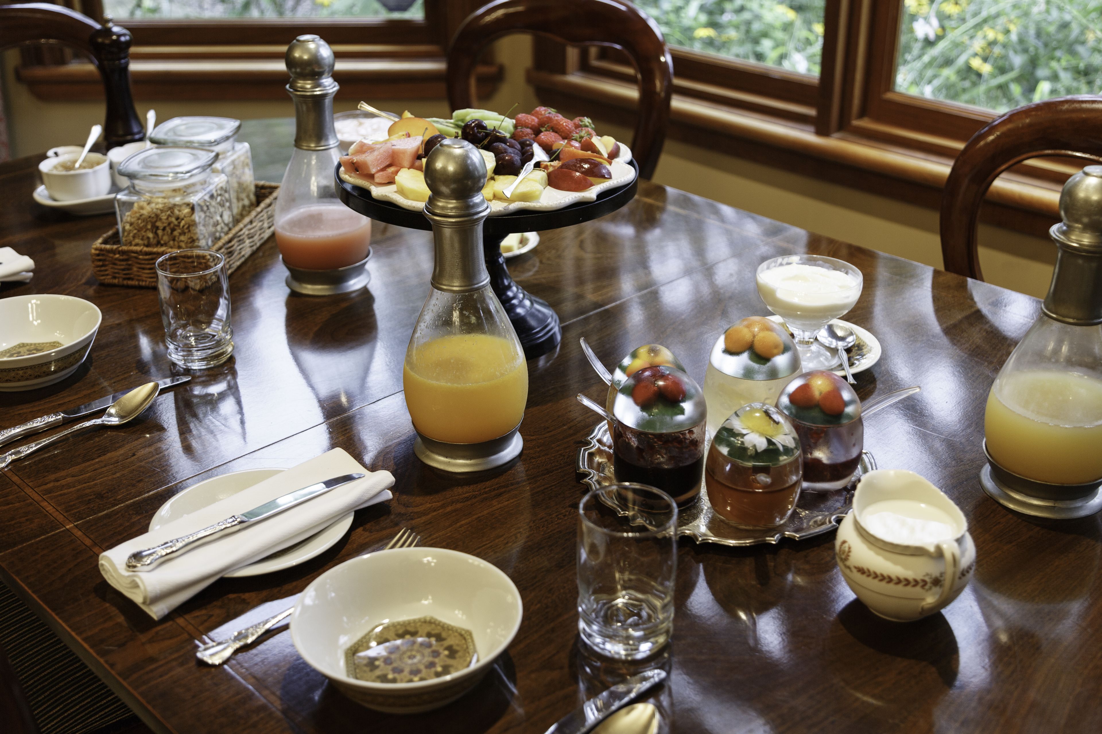 Una mesa de comedor dispuesta con diversos alimentos, bebidas y aderezos.