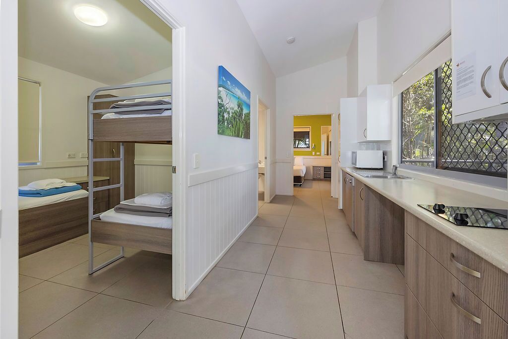 A compact hotel room with a bunk bed, a kitchenette, and a bathroom.