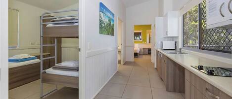 A compact hotel room with a bunk bed, a kitchenette, and a bathroom.